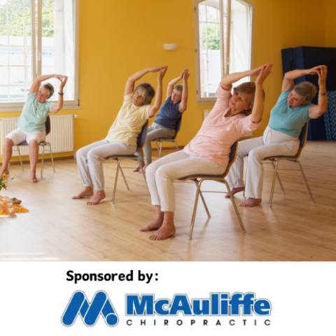 Adults class doing chair yoga.