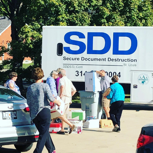 Secure Document Destruction Company truck with people unloading cars of paper documents to shred. 